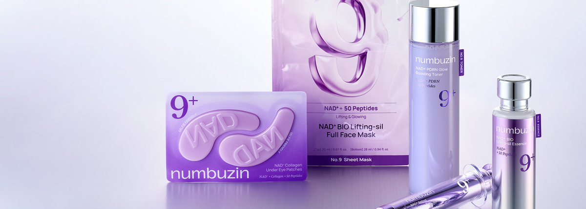 Numbuzin skincare set featuring a purple NAD+ lifting face mask sheet, a purple pump bottle, a smaller clear bottle with a silver cap, and a syringe applicator, arranged on a reflective light gray surface with a matching purple product box behind them.