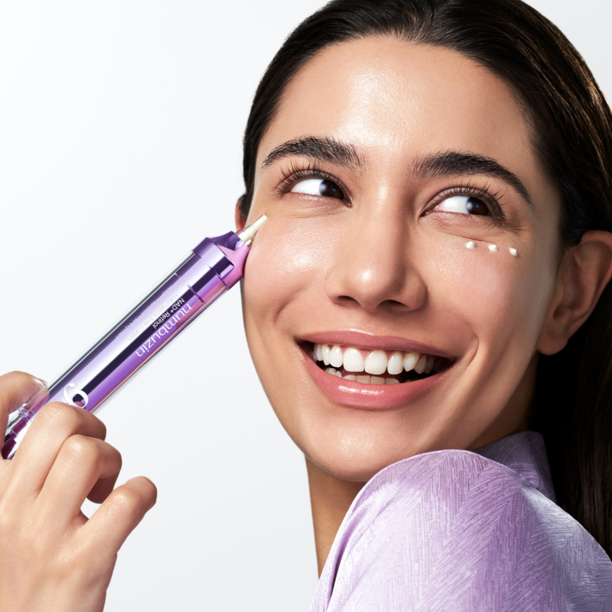 Model placing an eye cream on under eyes. 