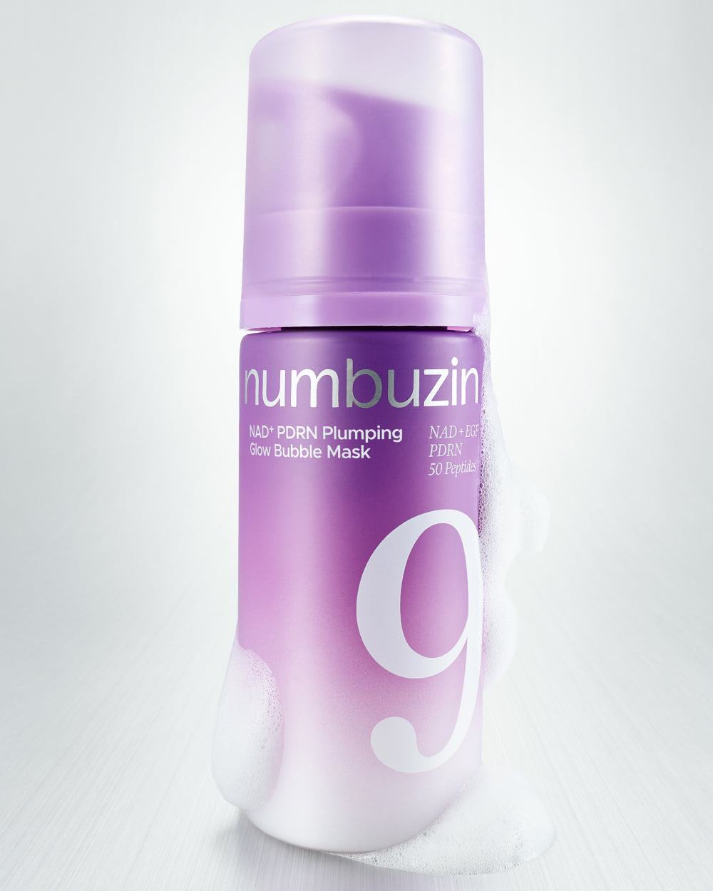 A purple and white cylindrical bottle of numbuzin Glow Bubble Mask with a matching cap, shown on a light gray background with a few bubbles at the base.